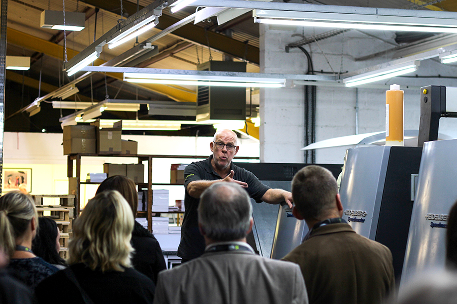 Group of people watching a man explain a piece of equipment