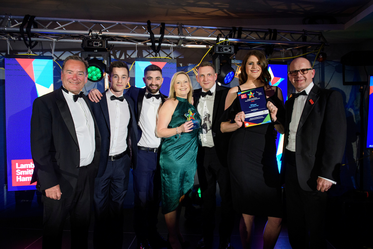 Picture of a group of people in formal evening wear holding trophies and certificates and smiling