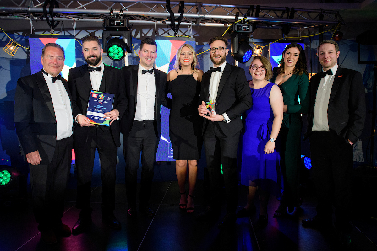 Group of people in eveningwear holding a framed certificate and smiling