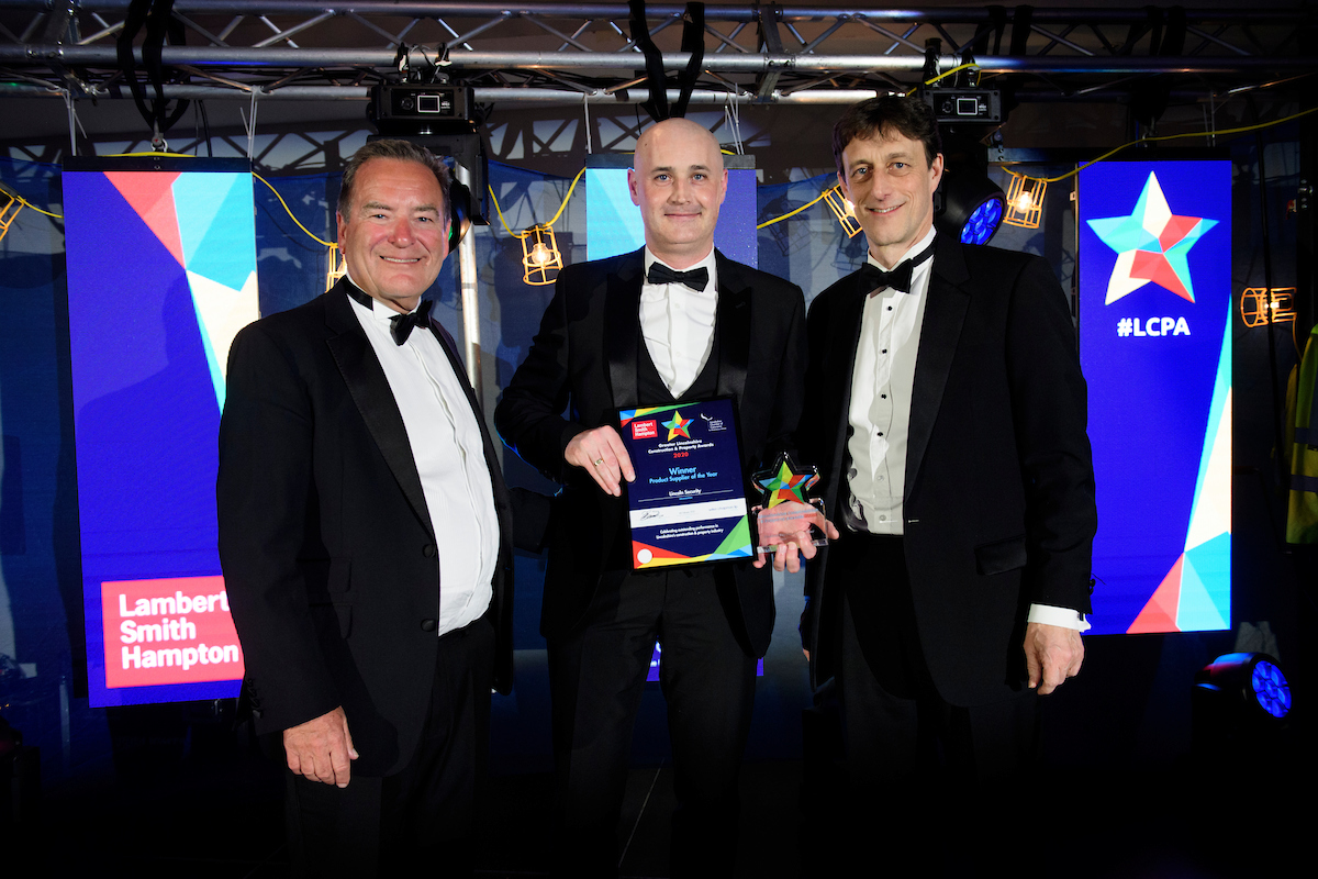 Three men in formal evening wear holding trophies and certificates and smiling