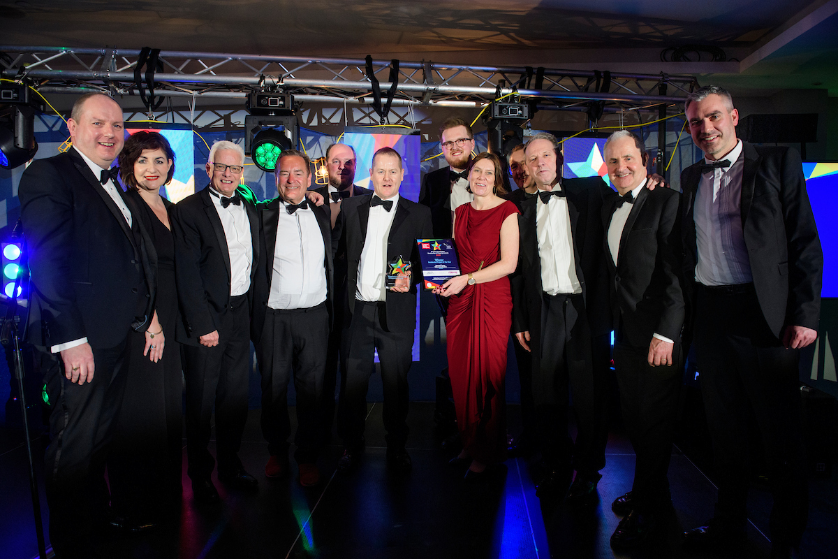 Picture of a group of people in formal evening wear holding trophies and certificates and smiling