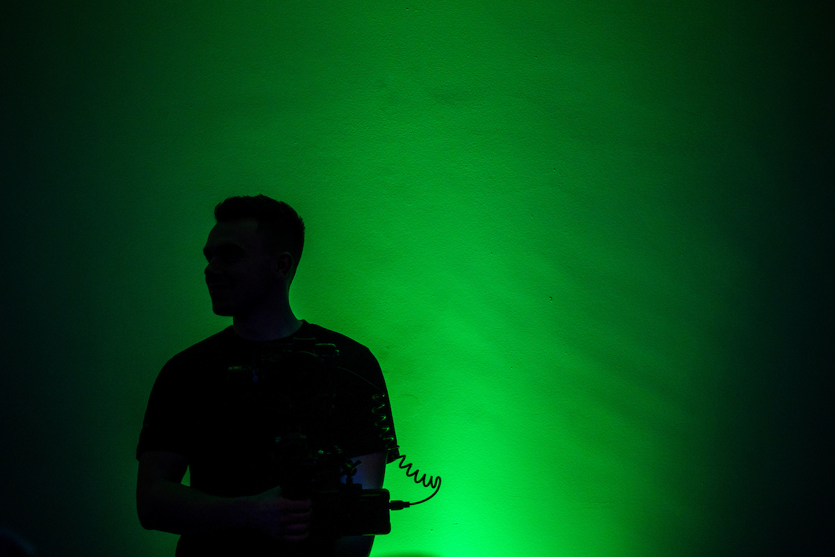 Person with video camera backlit in green light