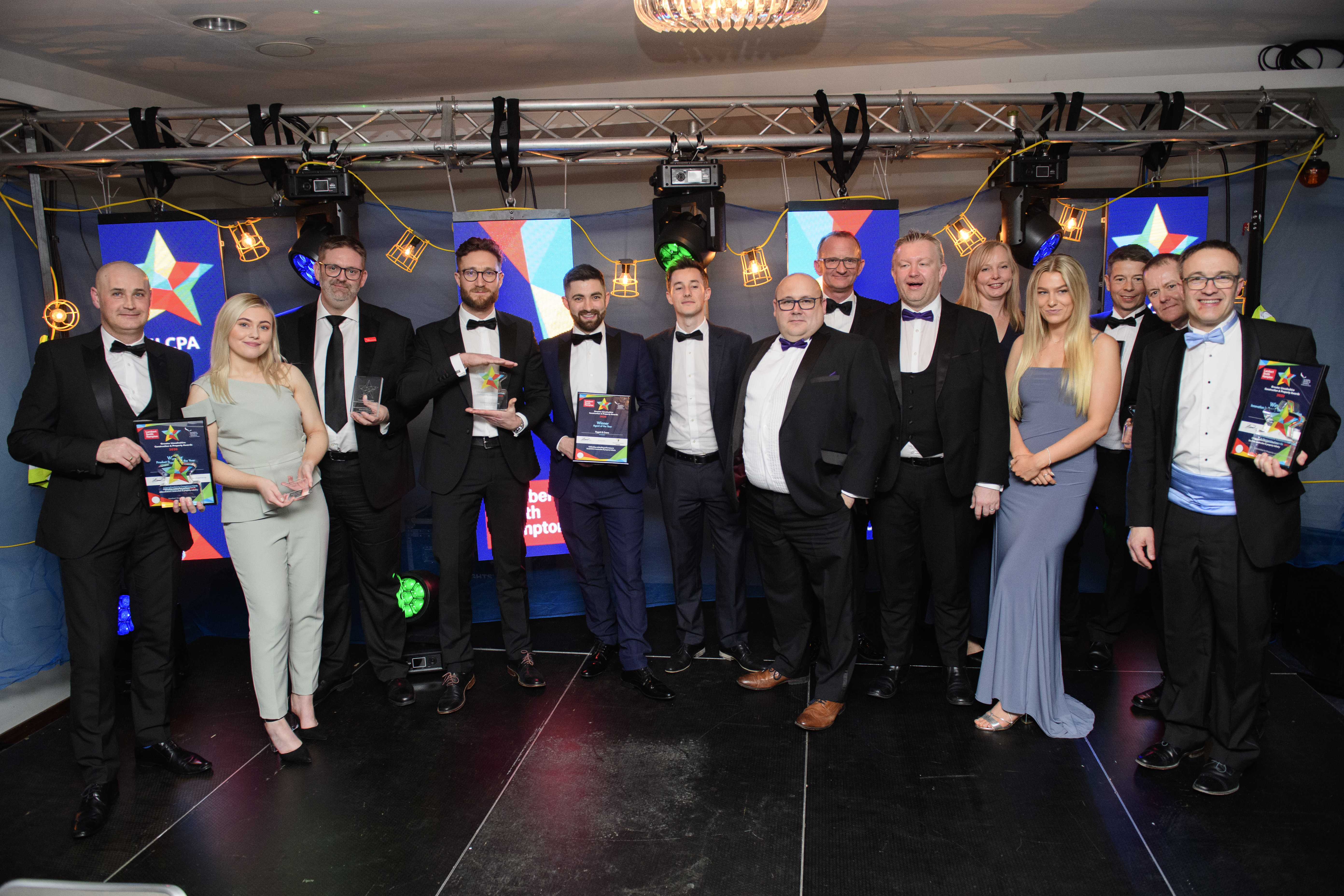 Picture of a group of people in formal evening wear holding trophies and certificates and smiling