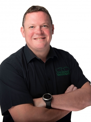 Man with folded arms and dark shirt smiling at camera