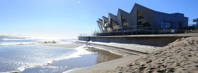 Modern building next to beach with sand in the foreground