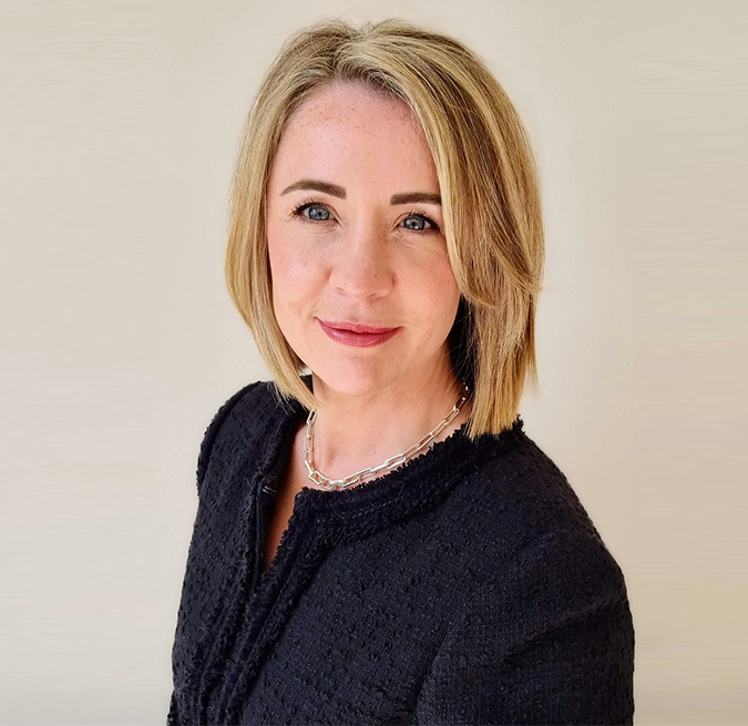 Jo Hardy, a woman with short blonde hair wearing black clothing on blank background