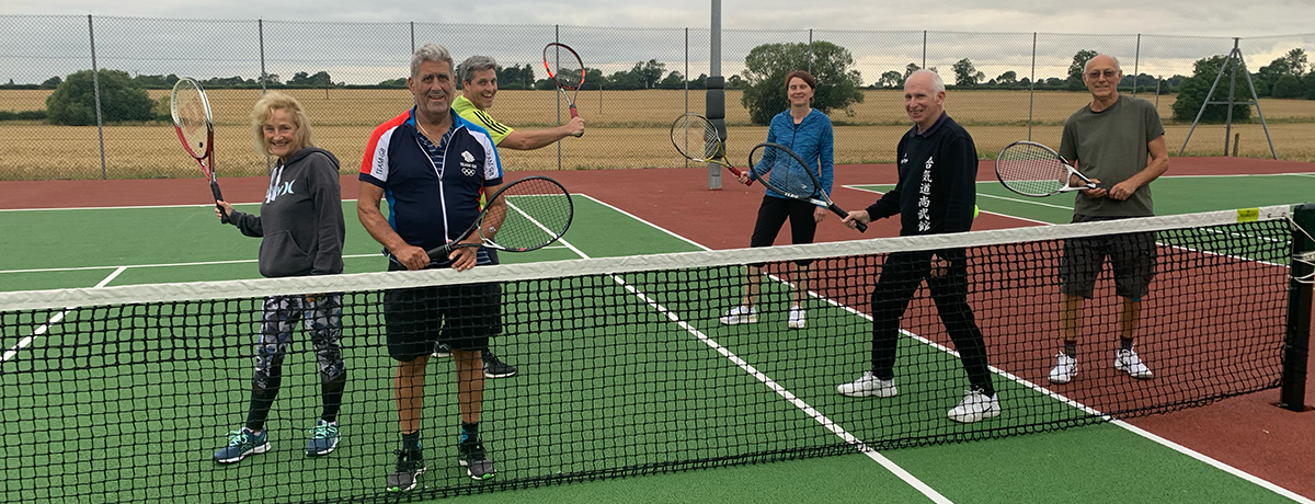 Group of men and women holding tennis rackets on a tennis court