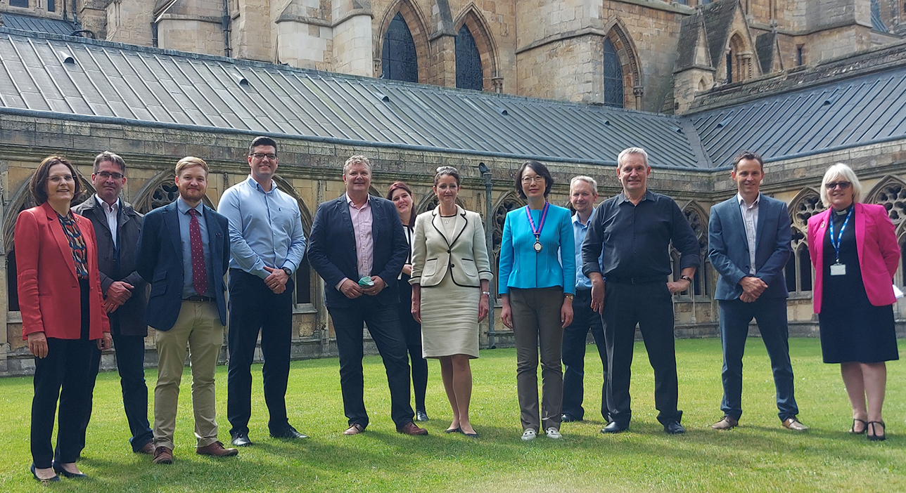 Group of men and women posing and smiling in front of Lincoln Cathedral