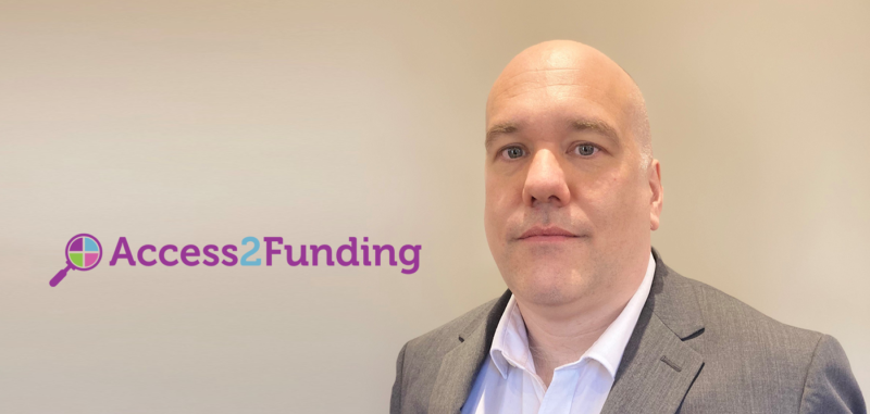 Leslie Maloney of Access2funding, a bald man in suit on beige background with purple Access2Funding logo