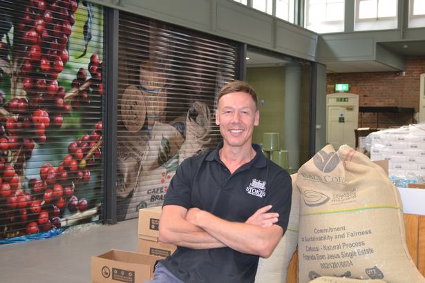 Nick Peel MD at Stokes Tea & Coffee, a man with folded arms leaning against large coffee bean bags in a warehouse