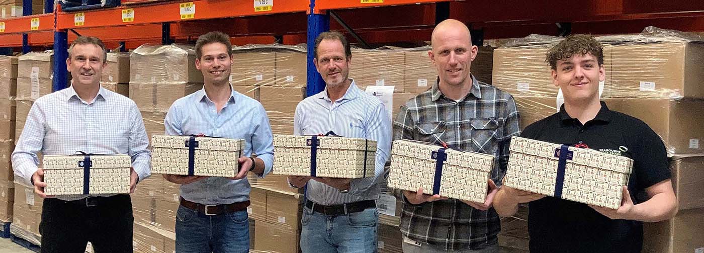 Five men holding gift boxes from British Hamper Company in a warehouse setting