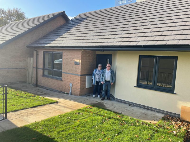 People at the front door of a newly built bungalow, developed by social housing developers Ongo.