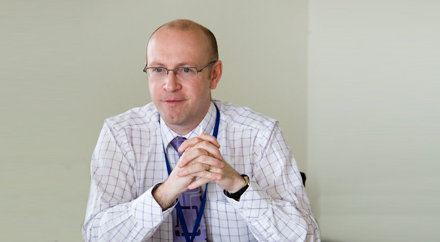 Nick Chambers, CEO of LACE Housing, a man wearing glasses, white shirt, hands clasped together looking away