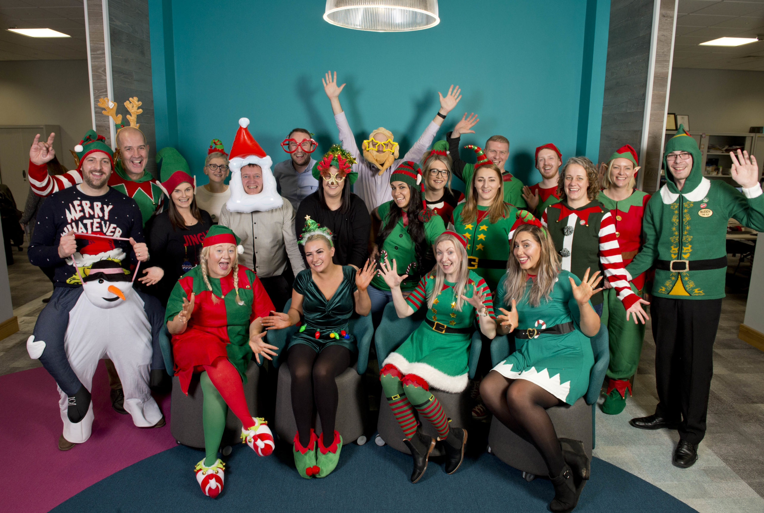 Large group of people sitting and standing wearing festive Christmas outfits and cheering