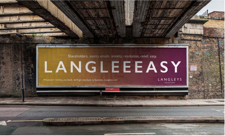 Billboard on underpass in orange to pink gradient with white text Langleeeeeasy