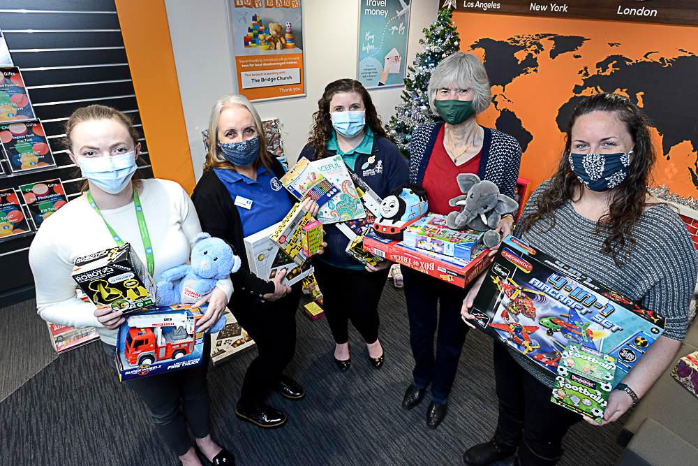 Five women holding children's toys in a Lincolnshire Co-op travel agency, wearing face masks