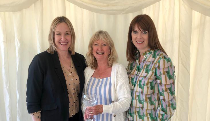 Three women smiling and posing for picture. 