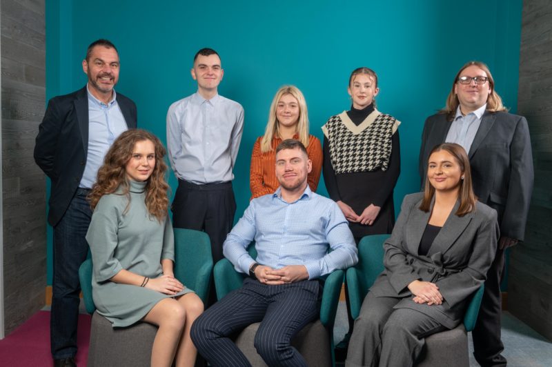 Group of people sitting and standing against blue background