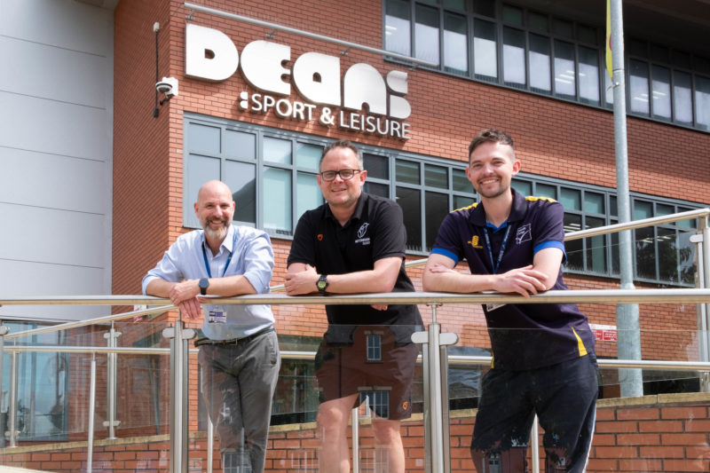 Three men standing in front of Lincoln College's Deans Sports & Leisure centre.