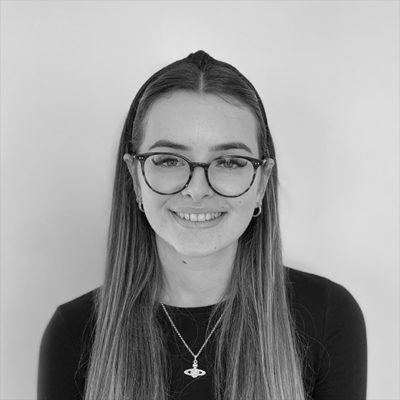 A black and white image of a female wearing glasses smiling at the camera.
